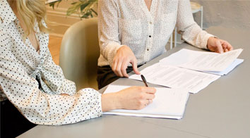 two women completing forms at desk polka dot shirt