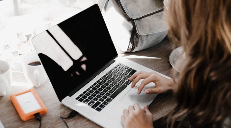 Girl using laptop with portable hard drive