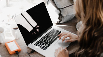 Girl using laptop with portable hard drive