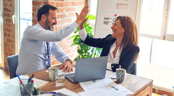 Man and woman high-fiving over successful business deal