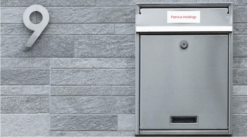 Silver letterbox for number 9 on grey brick wall