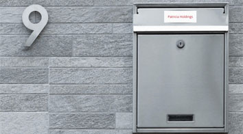 Silver letterbox for number 9 on grey brick wall